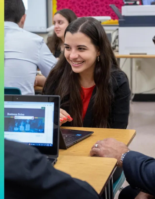 Girl with a laptop smiling in a classroom
